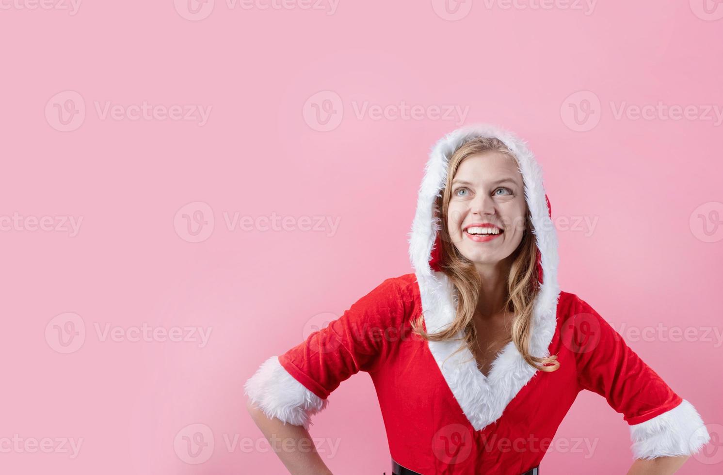 closeup of caucasian happy woman wearing santa clothes against pink background, copy space photo