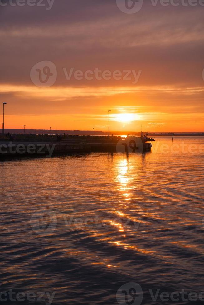 puesta de sol en suecia en el puerto del lago vaetten. faro en el fondo foto