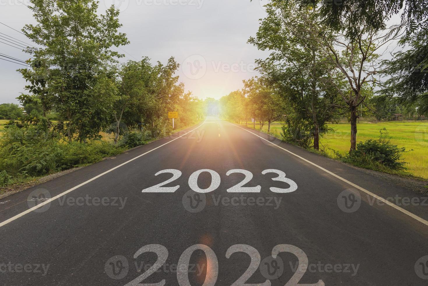 concepto de autopista para la planificación empresarial, la palabra 2023 escrita en la carretera en medio de una carretera asfaltada vacía al atardecer dorado y el hermoso cielo azul. foto