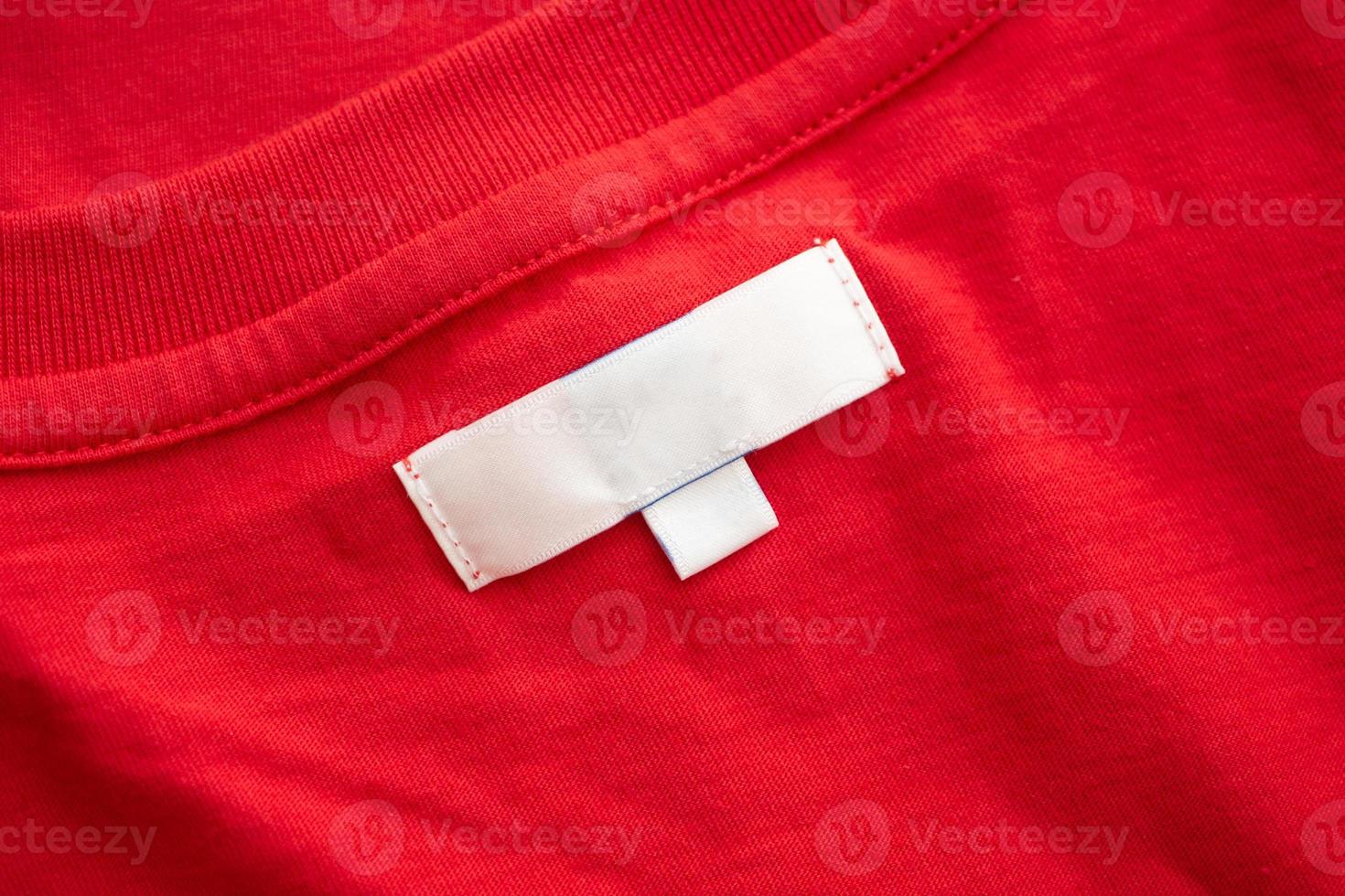 White blank clothing tag label on new red cotton shirt fabric texture background photo