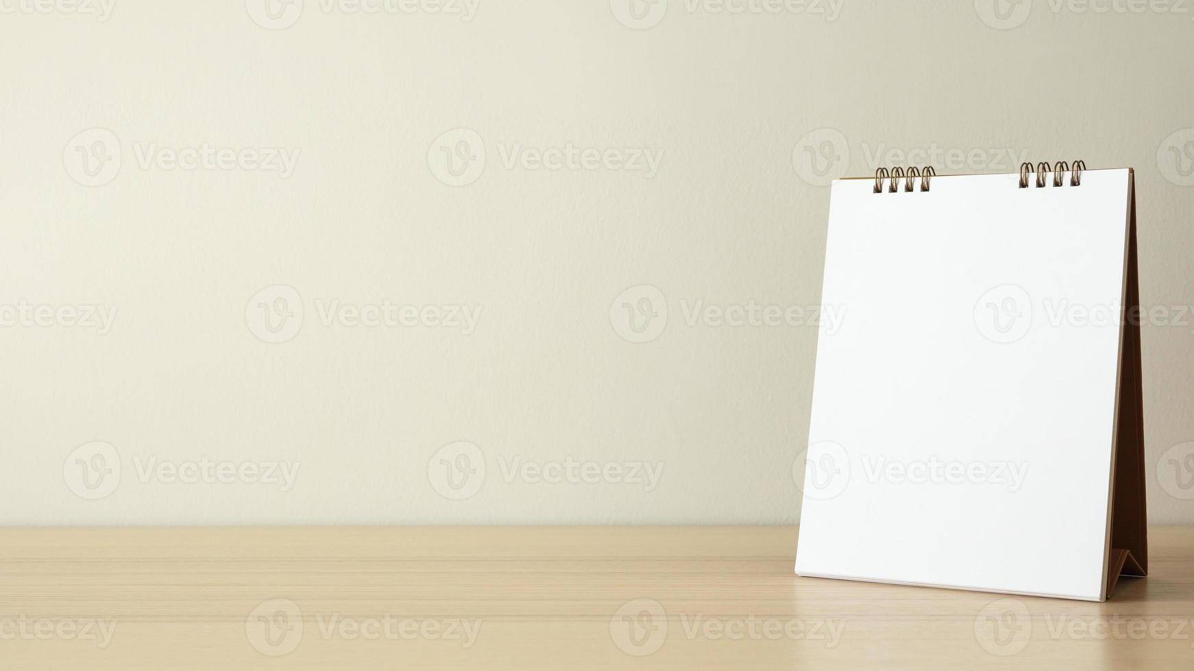 Blank white calendar page close up on wood table with white wall background photo