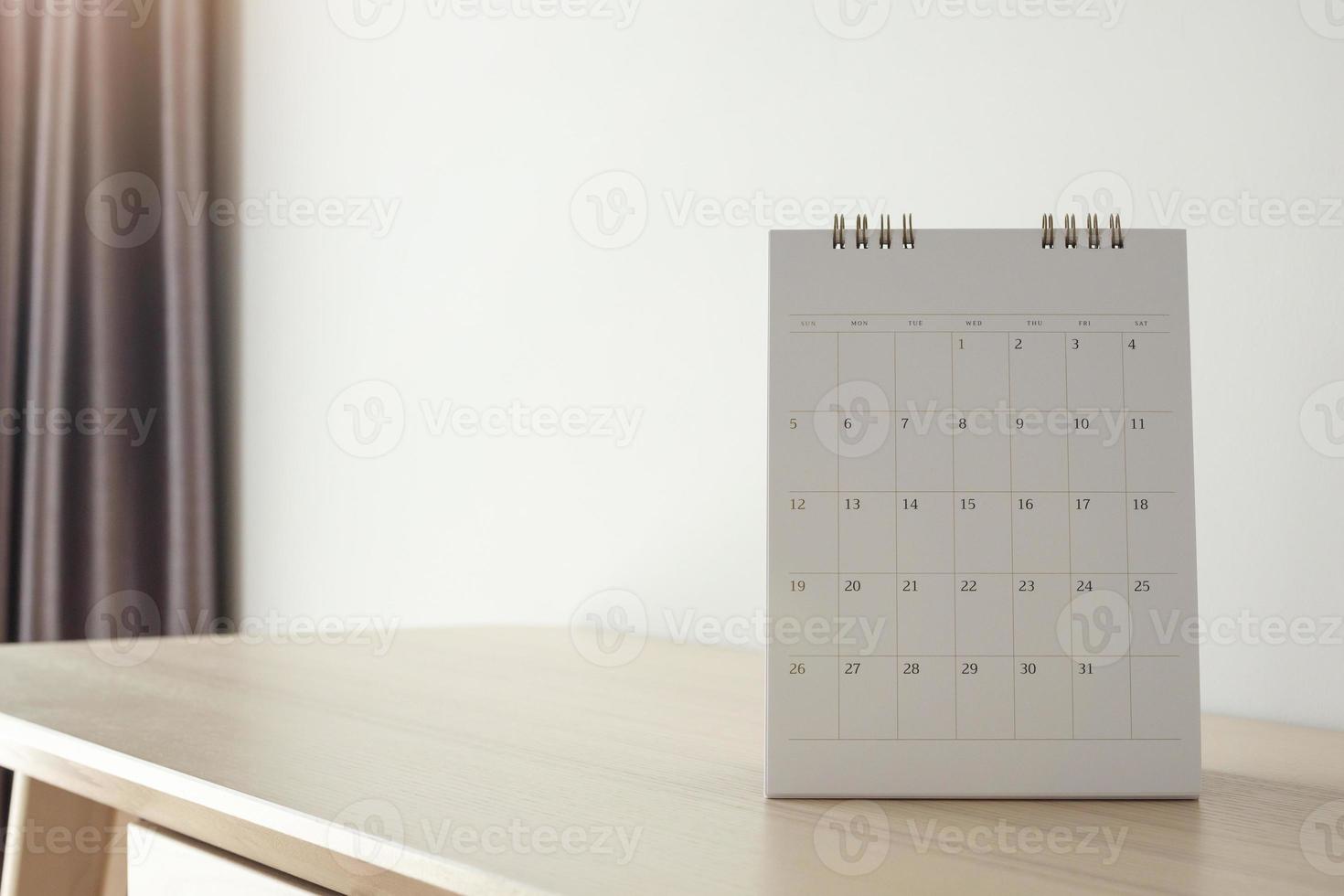 página del calendario de cerca en la mesa de madera con fondo de pared blanca foto