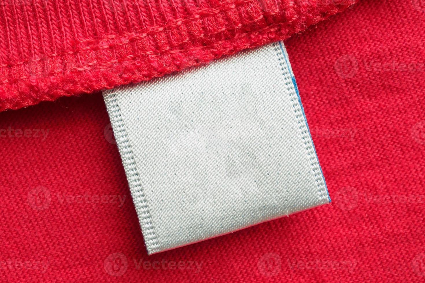 White blank laundry care clothes label on red cotton shirt background photo
