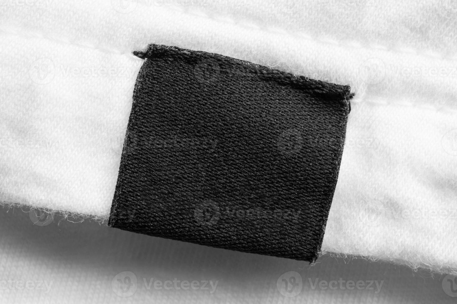 Black blank laundry care clothes label on white cotton shirt background photo