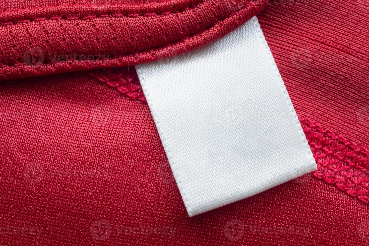 White blank laundry care clothes label on red polyester sport shirt background photo