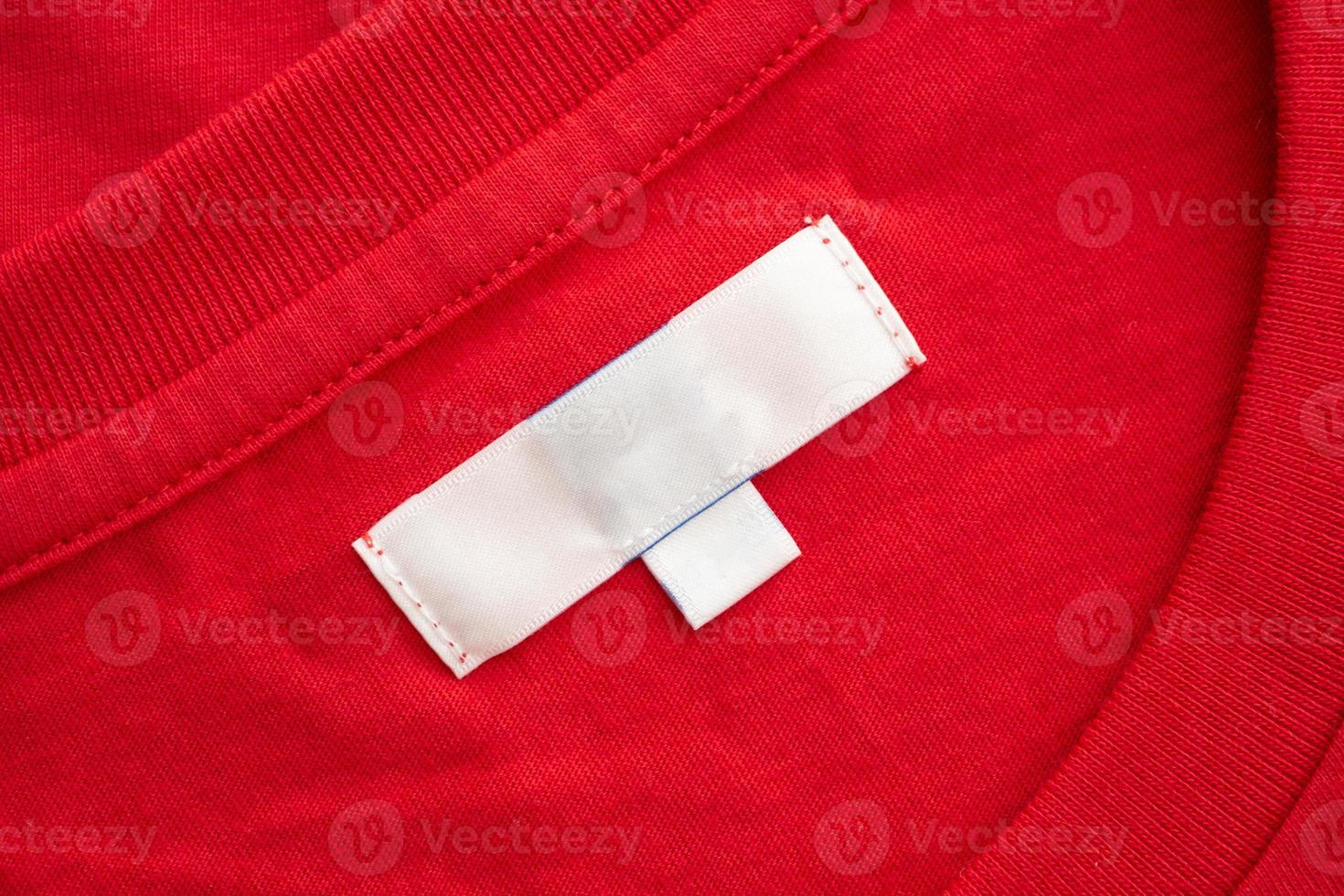 White blank clothing tag label on new red cotton shirt fabric texture background photo