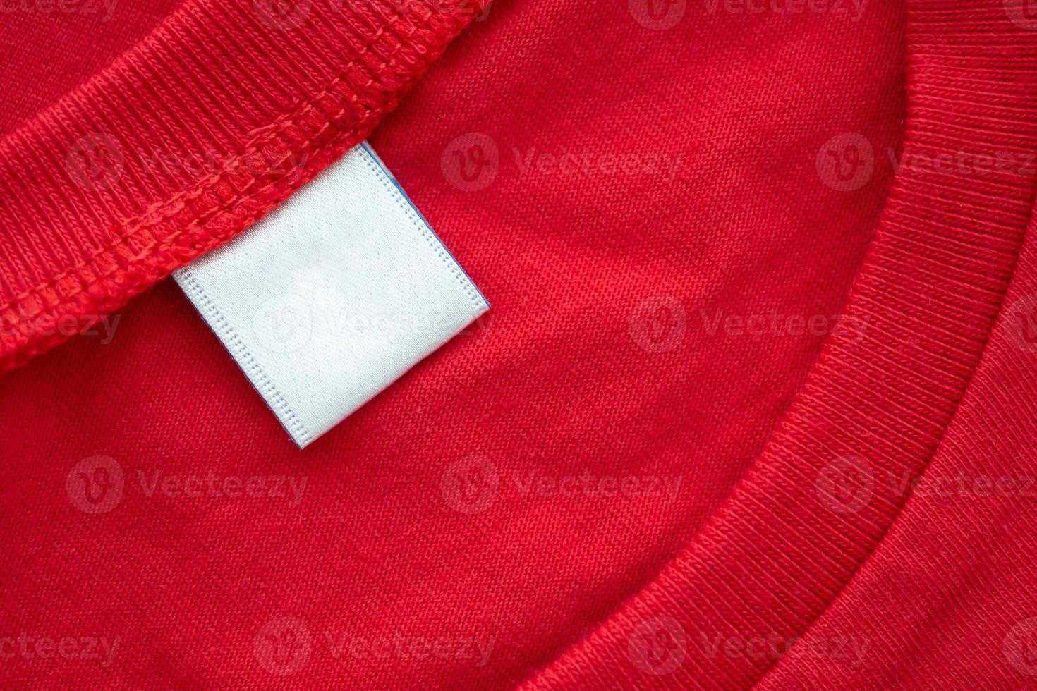 White blank clothing tag label on new red cotton shirt fabric texture background photo