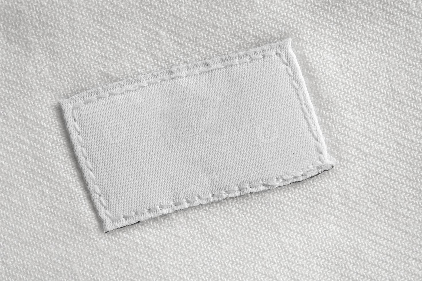 White blank laundry care clothes label on cotton shirt background photo