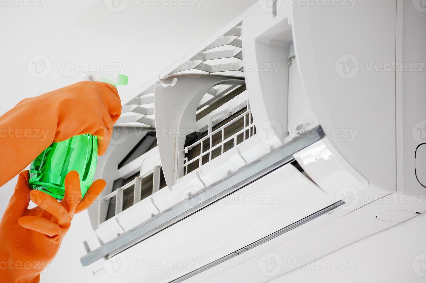 Asian man cleaning air conditioner with spray bottle photo