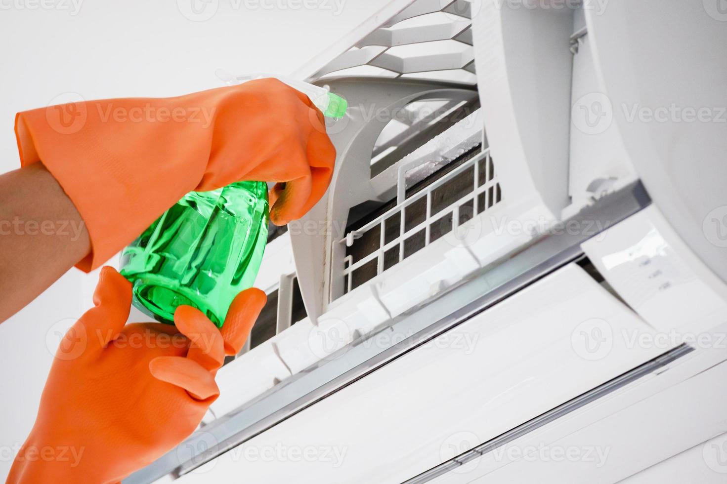 Asian man cleaning air conditioner with spray bottle photo