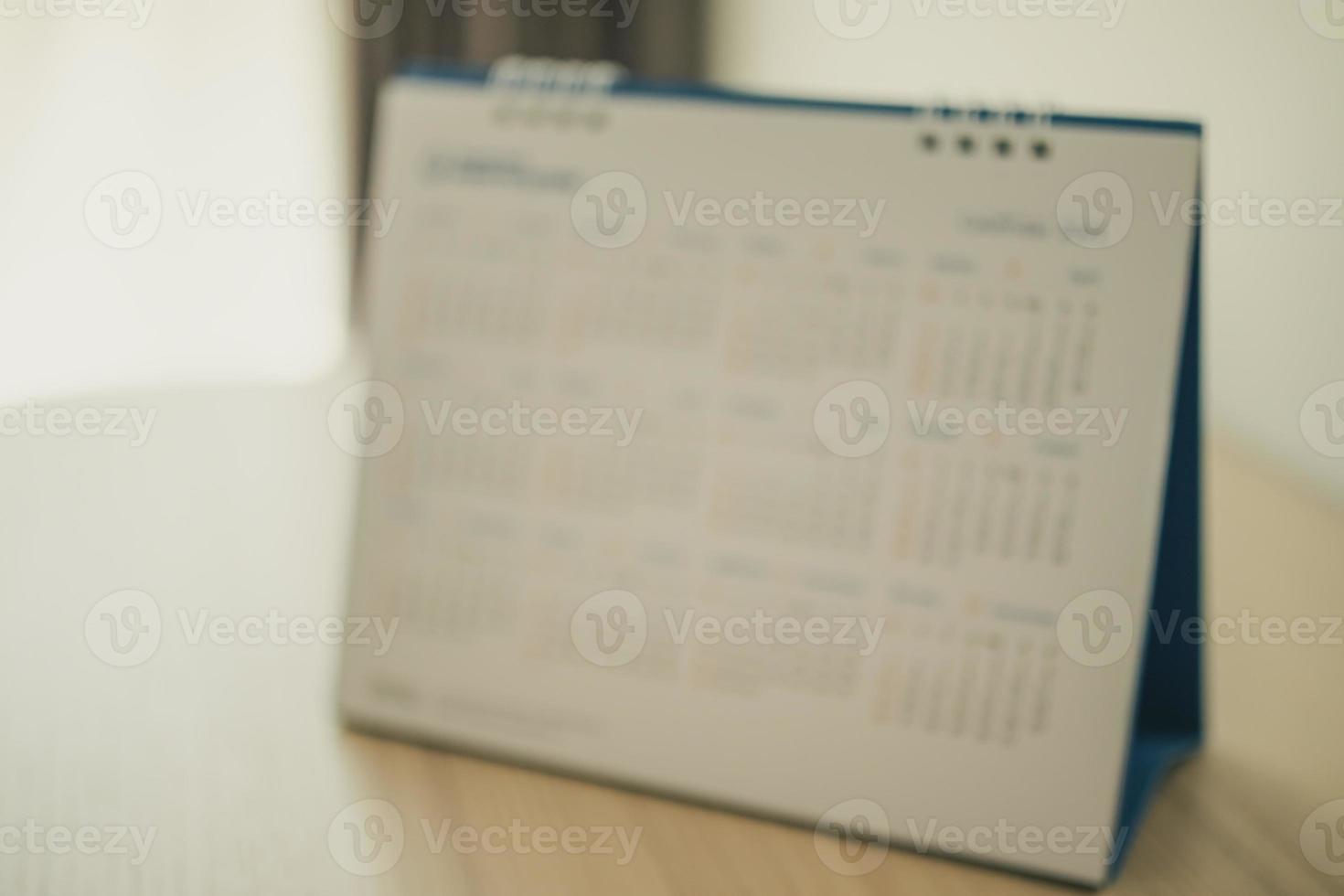 desenfoque de la página del calendario de cerca en el fondo de la mesa de madera concepto de reunión de cita de planificación empresarial foto