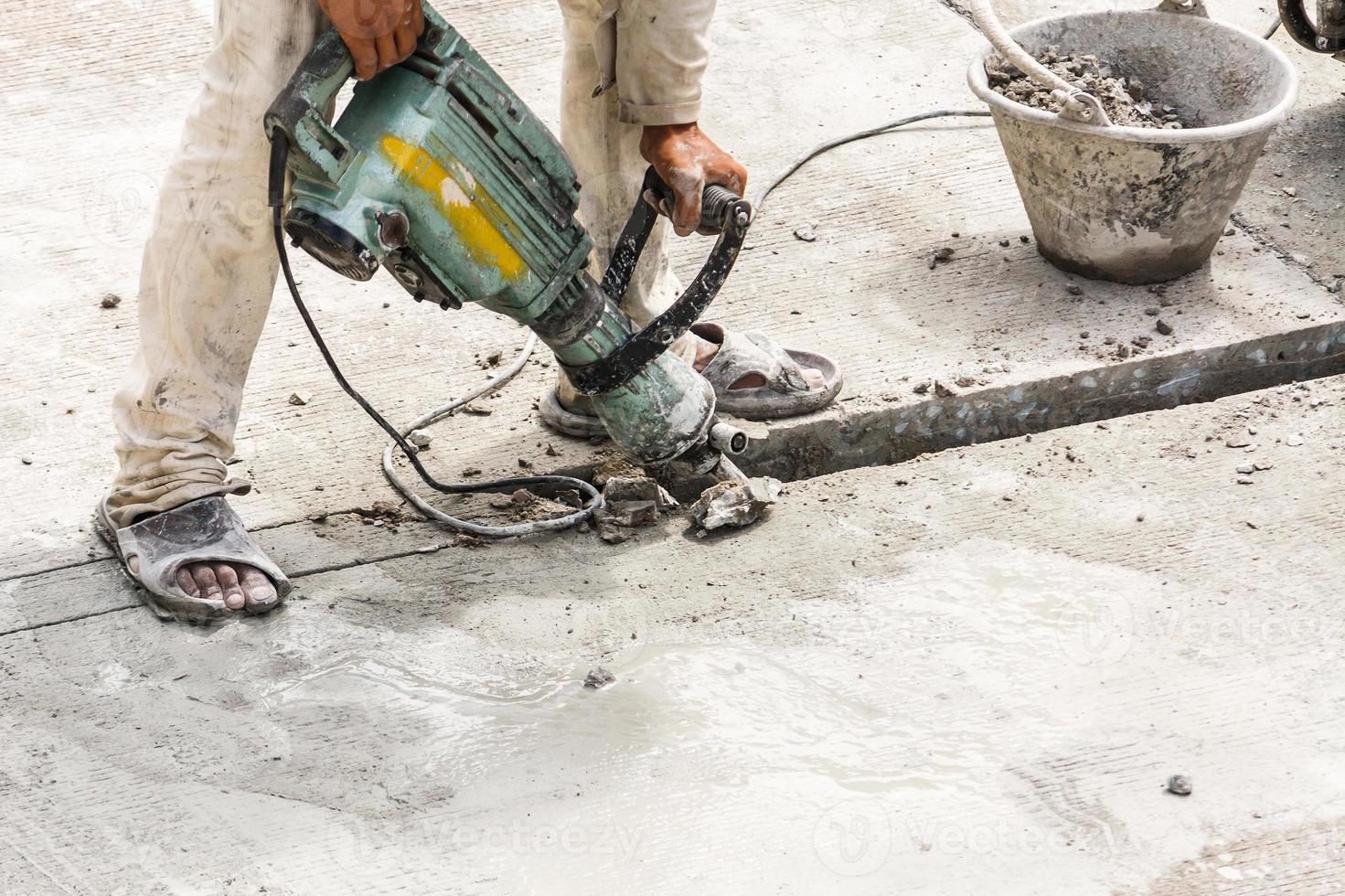 Construction worker using jackhammer drilling concrete surface photo