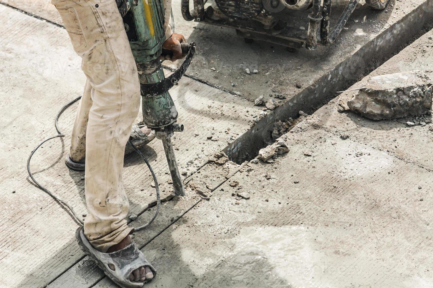 Construction worker using jackhammer drilling concrete surface photo