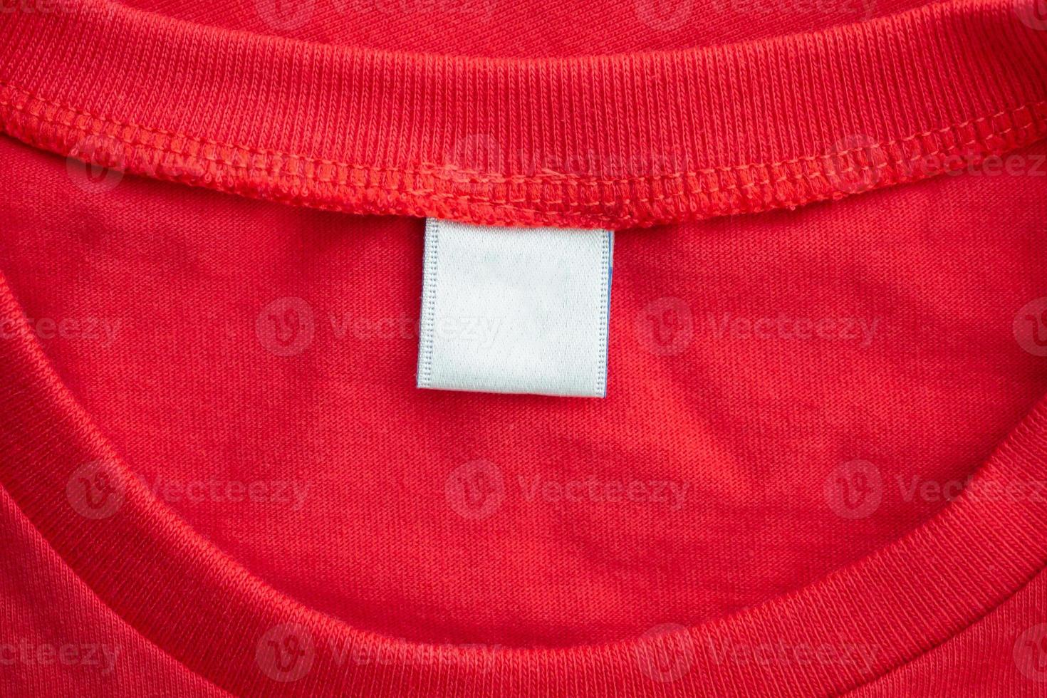 White blank clothing tag label on new red cotton shirt fabric texture background photo