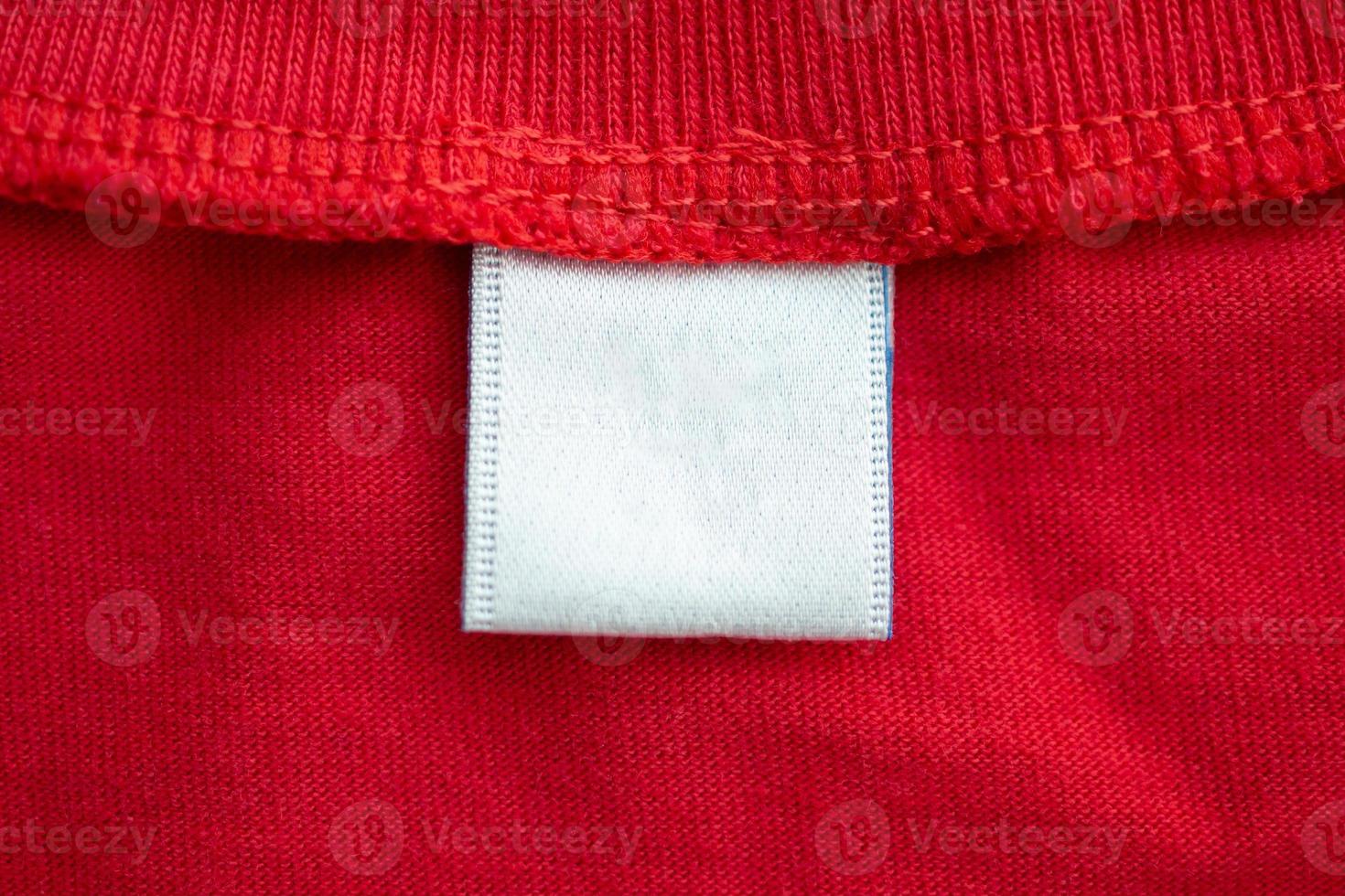 White blank clothing tag label on new red cotton shirt fabric texture background photo