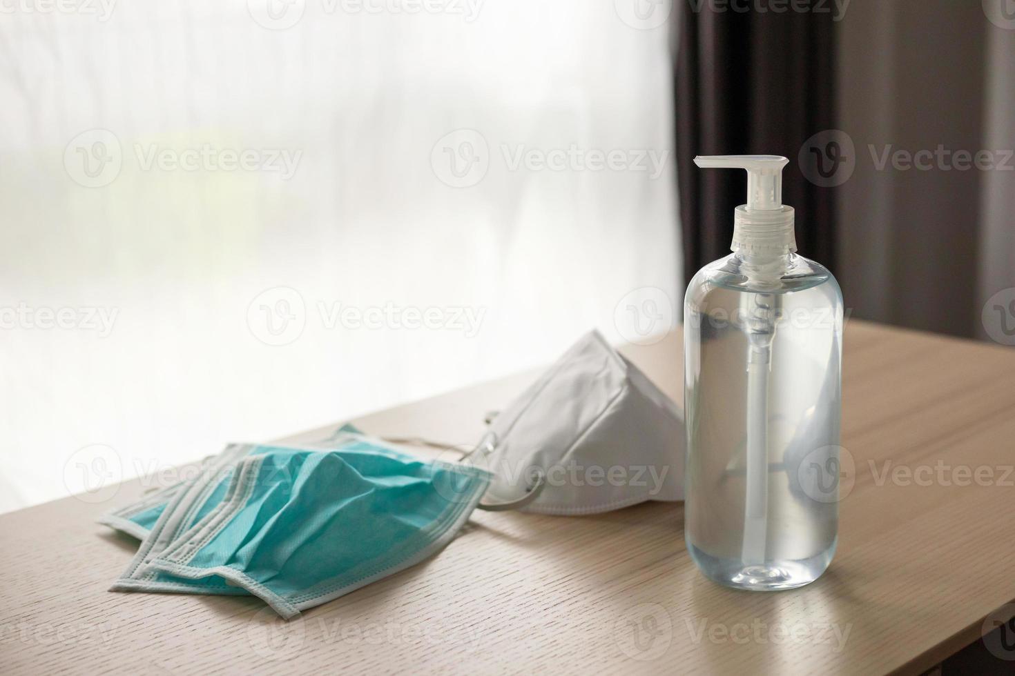 mascarilla médica con gel desinfectante de alcohol lavado a mano en mesa de madera para el concepto de prevención del coronavirus covid-19 foto