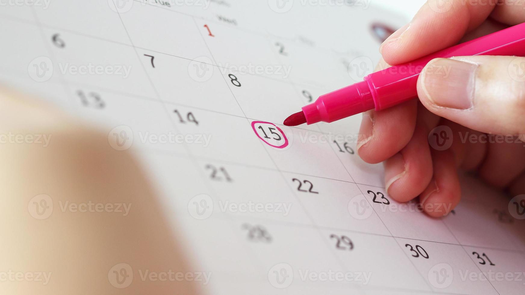 Hand with pen mark at 15th on calendar date photo