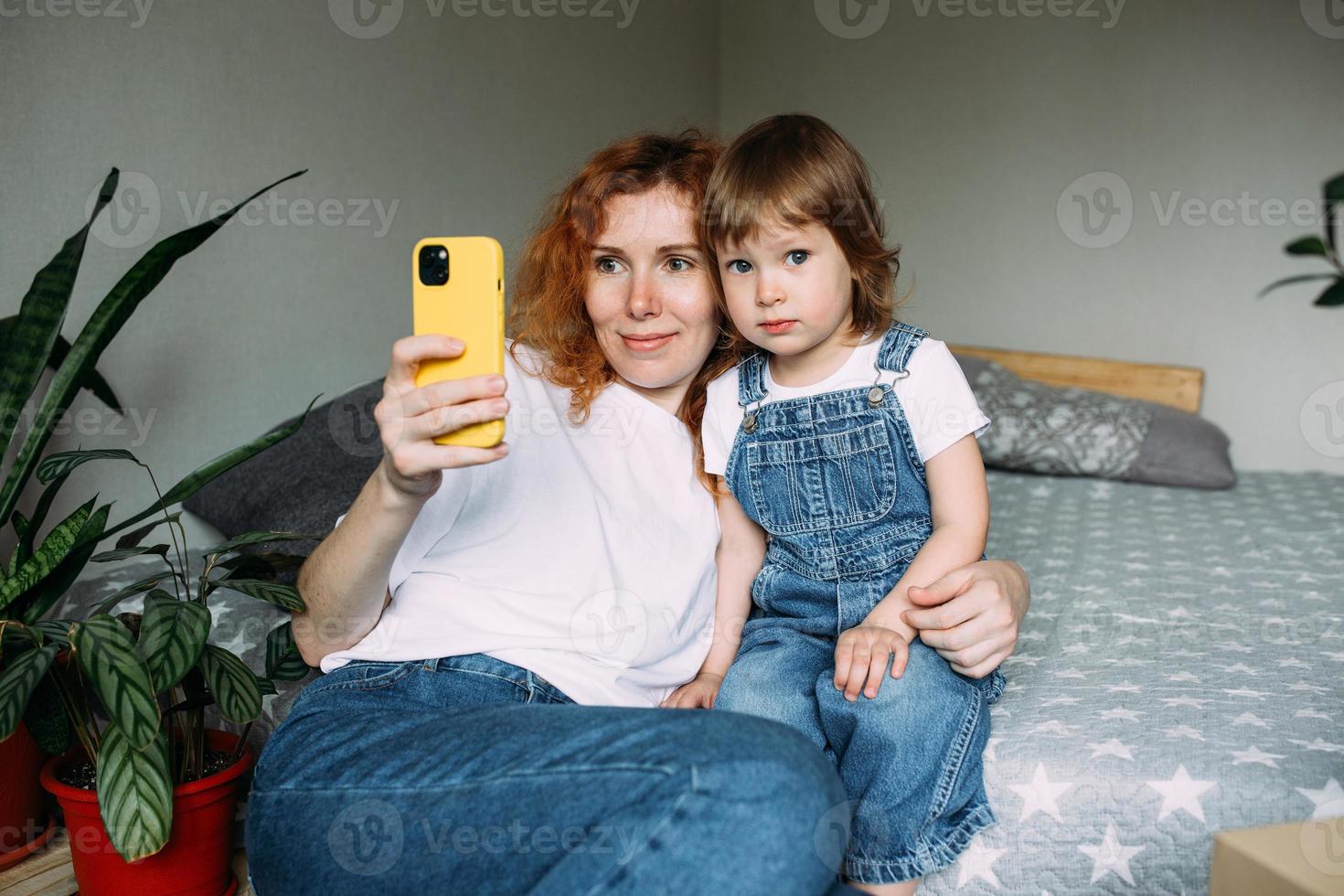 la joven madre y el niño toman fotos juntos en casa, se divierten