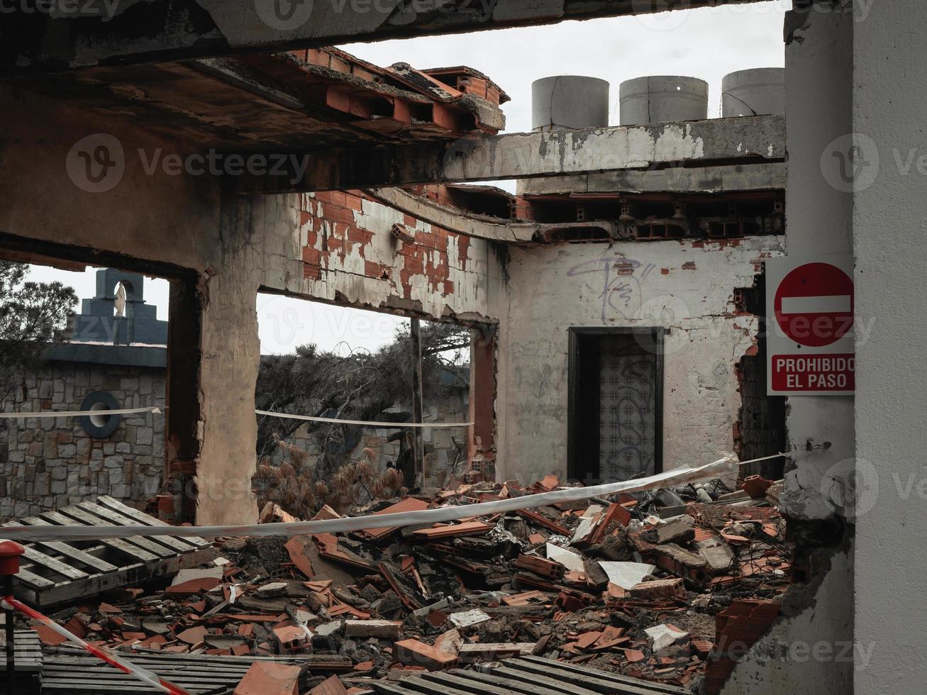 ruinas de un edificio con techo roto y un cartel que prohíbe el paso foto