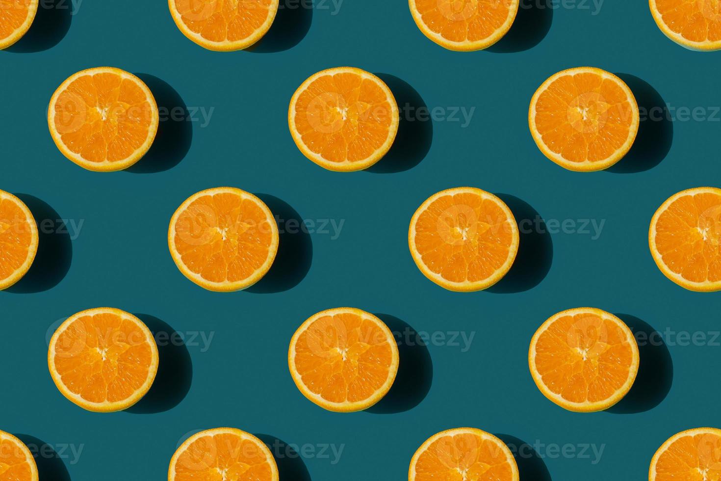 seamless pattern of ripe tasty orange cut in half on a blue background photo