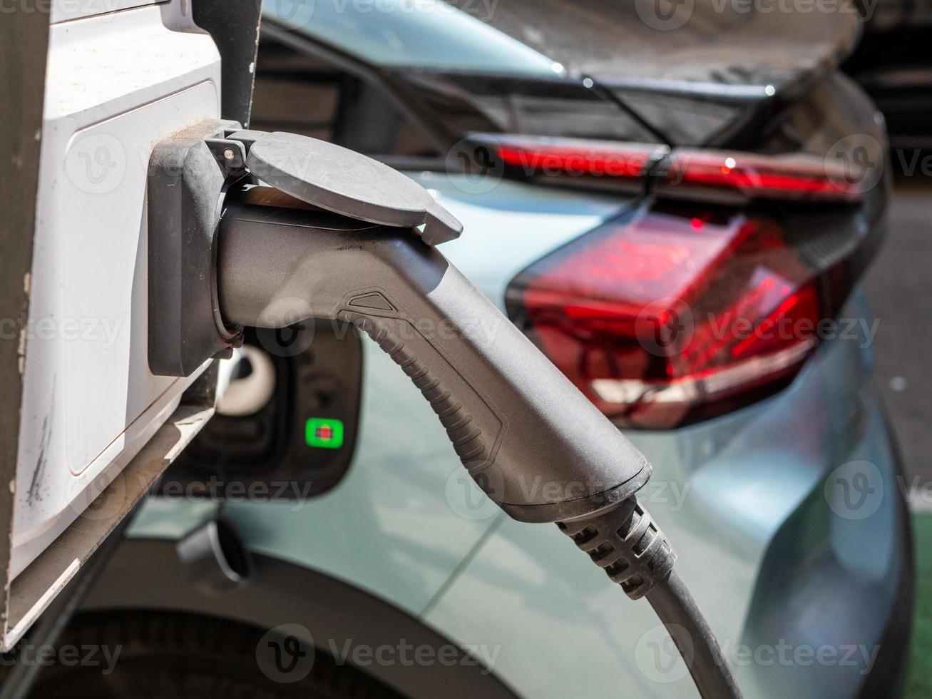 electric car charging. charging cable handle on the background of the car in defocus photo
