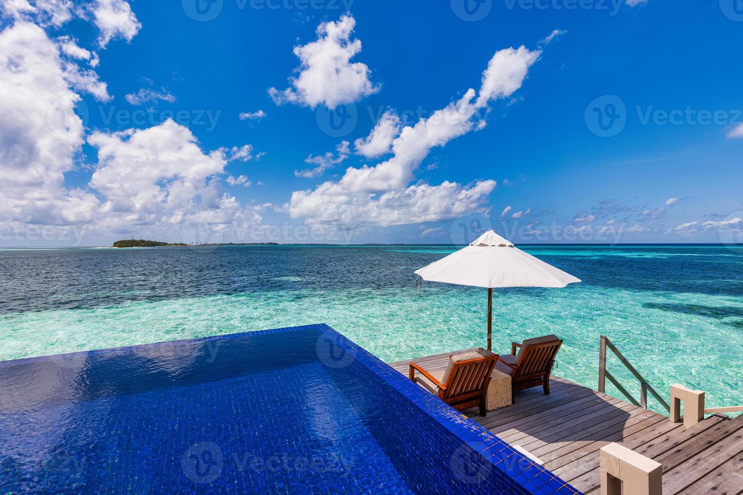 Deck chair with umbrellas at Maldives resort with infinity pool and beach, sea sky view. Luxury water villa, paradise island honeymoon, romantic couple destination. Summer relaxation leisure retreat photo
