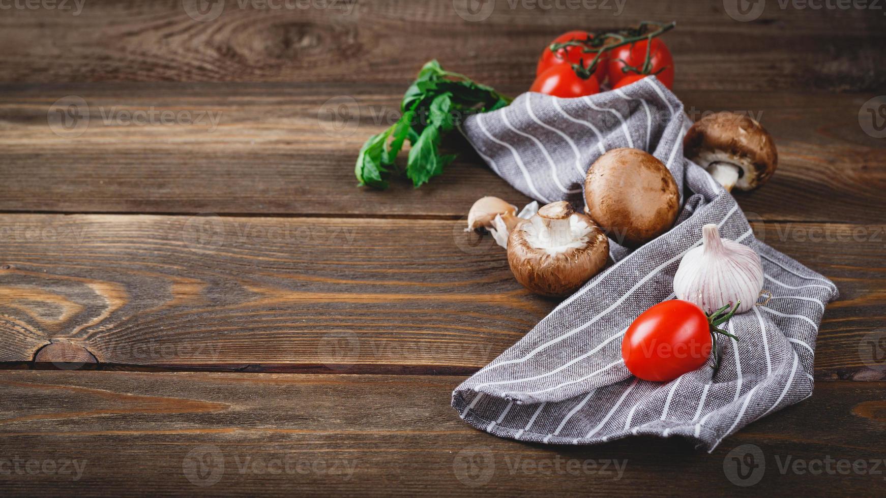 Tomatoes, garlic, champignons, parsley, pepper shaker, forks and napkin on wooden background photo