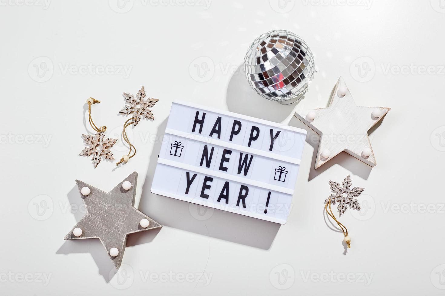 inscripción de caja de luz feliz año nuevo, bola de discoteca espejada y decoraciones de estrellas de madera foto