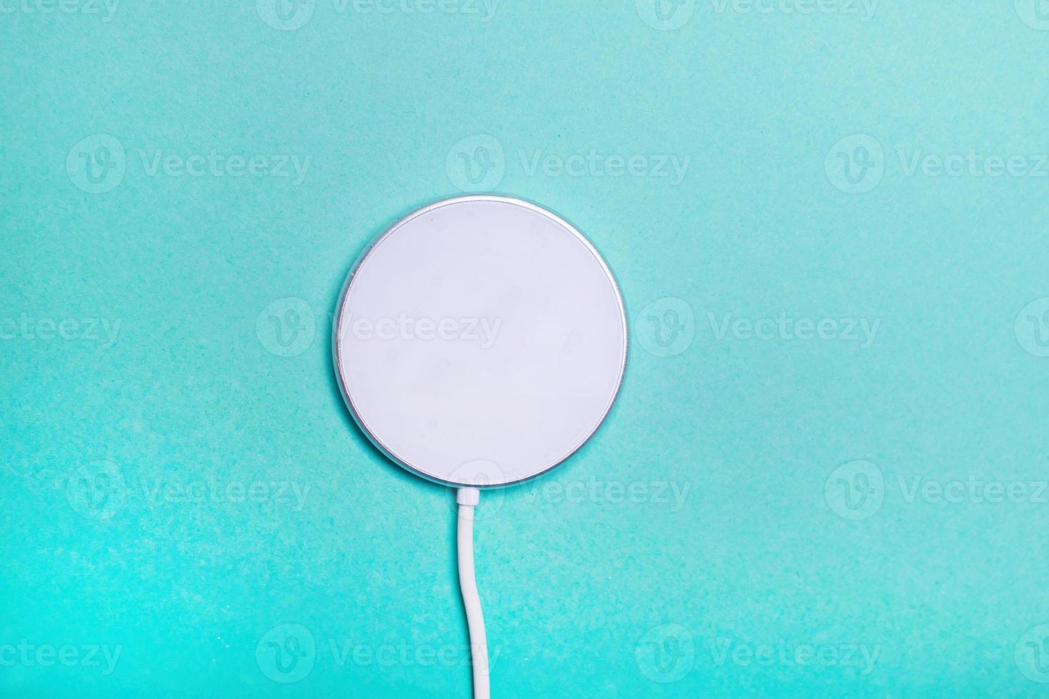 White wireless charging pad for smartphone on the green background. photo