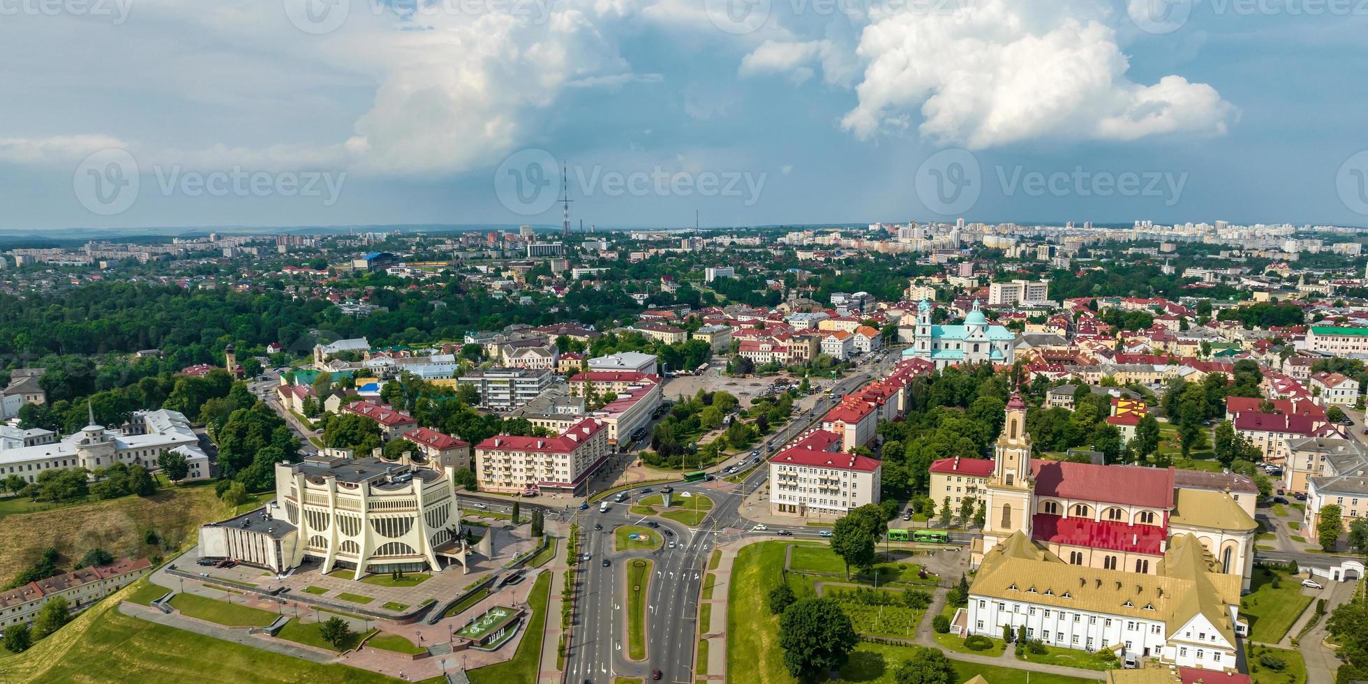 aerial panoramic view from great height on red roofs of old big city with skyscrapers and white fluffy clouds photo