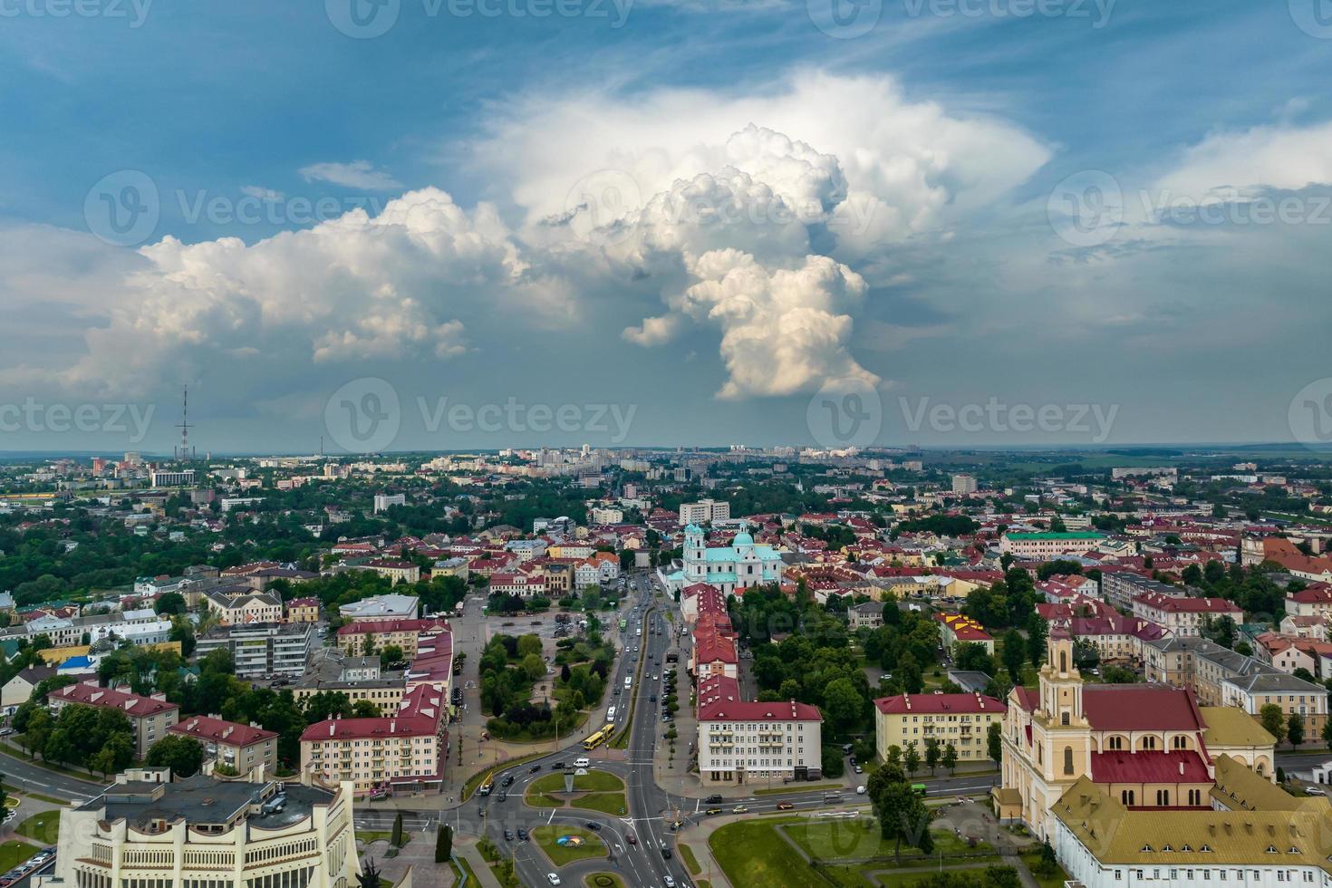 aerial panoramic view from great height on red roofs of old big city with skyscrapers and white fluffy clouds photo