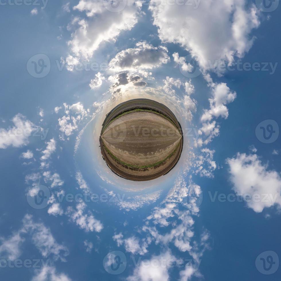 tiny planet in blue sky with beautiful clouds with transformation of spherical panorama 360 degrees. Spherical abstract aerial view. Curvature of space. photo