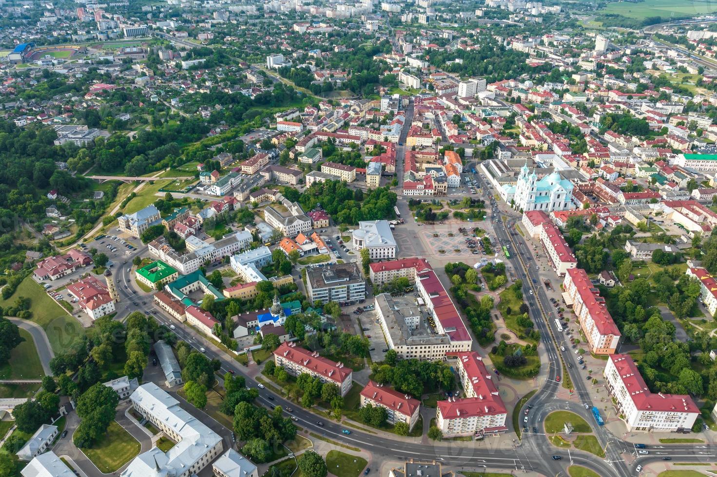 aerial panoramic view from great height on red roofs of old big city with skyscrapers and white fluffy clouds photo
