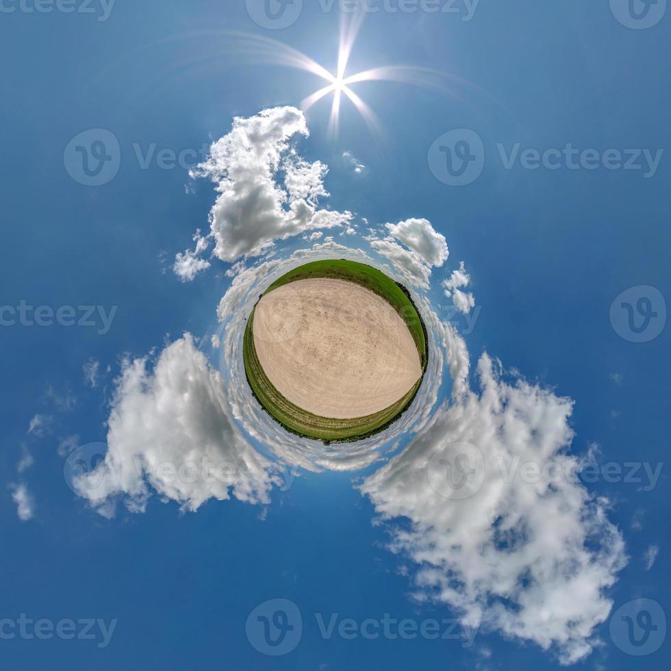 tiny planet in blue sky with beautiful clouds with transformation of spherical panorama 360 degrees. Spherical abstract aerial view. Curvature of space. photo