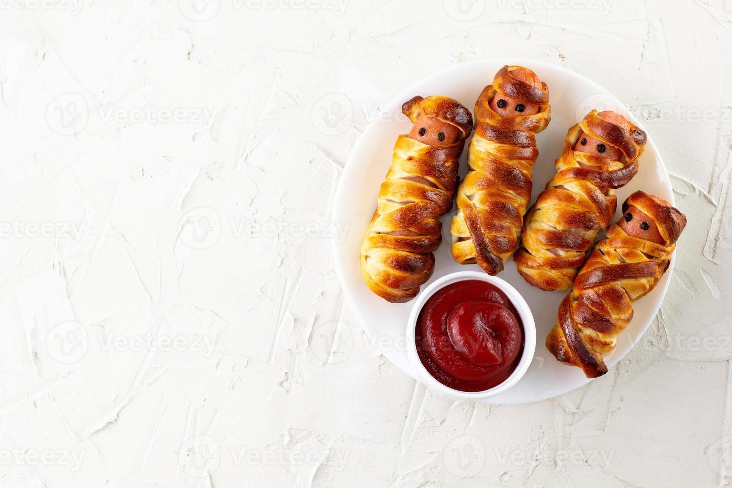 Scary sausage mummies in dough for kids party. Funny crazy Halloween food for children. photo