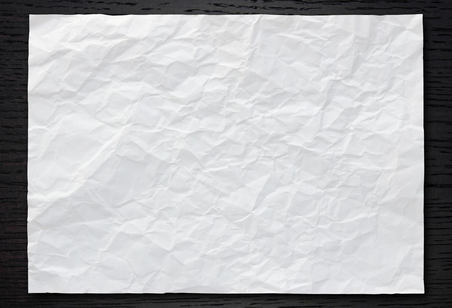 White crumpled paper on dark wood background photo