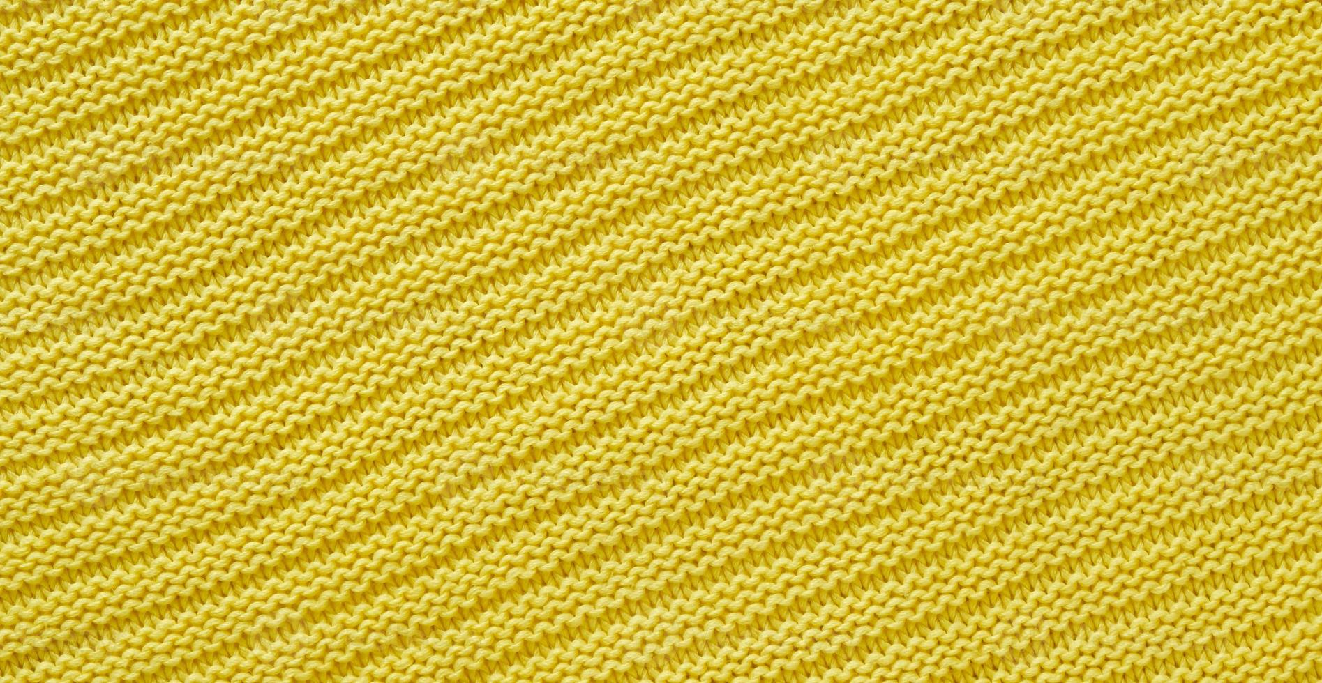 Texture of smooth knitted yellow sweater with pattern. Top view, close-up. Handmade knitting wool or cotton fabric texture. Background of knitting patterns. photo