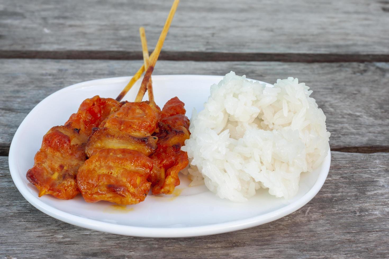 Grilled pork with sticky rice in white plate is a food that Thai people prefer to eat, There are general sales along the wayside. photo