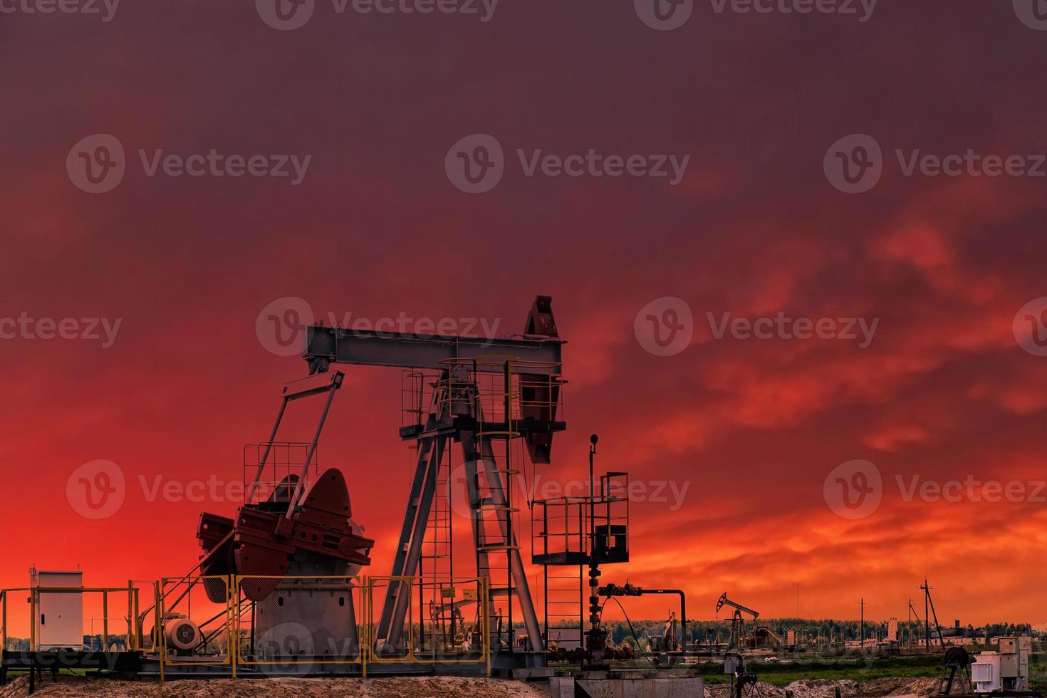 Oil drill rig and pump jack at sunset background. photo