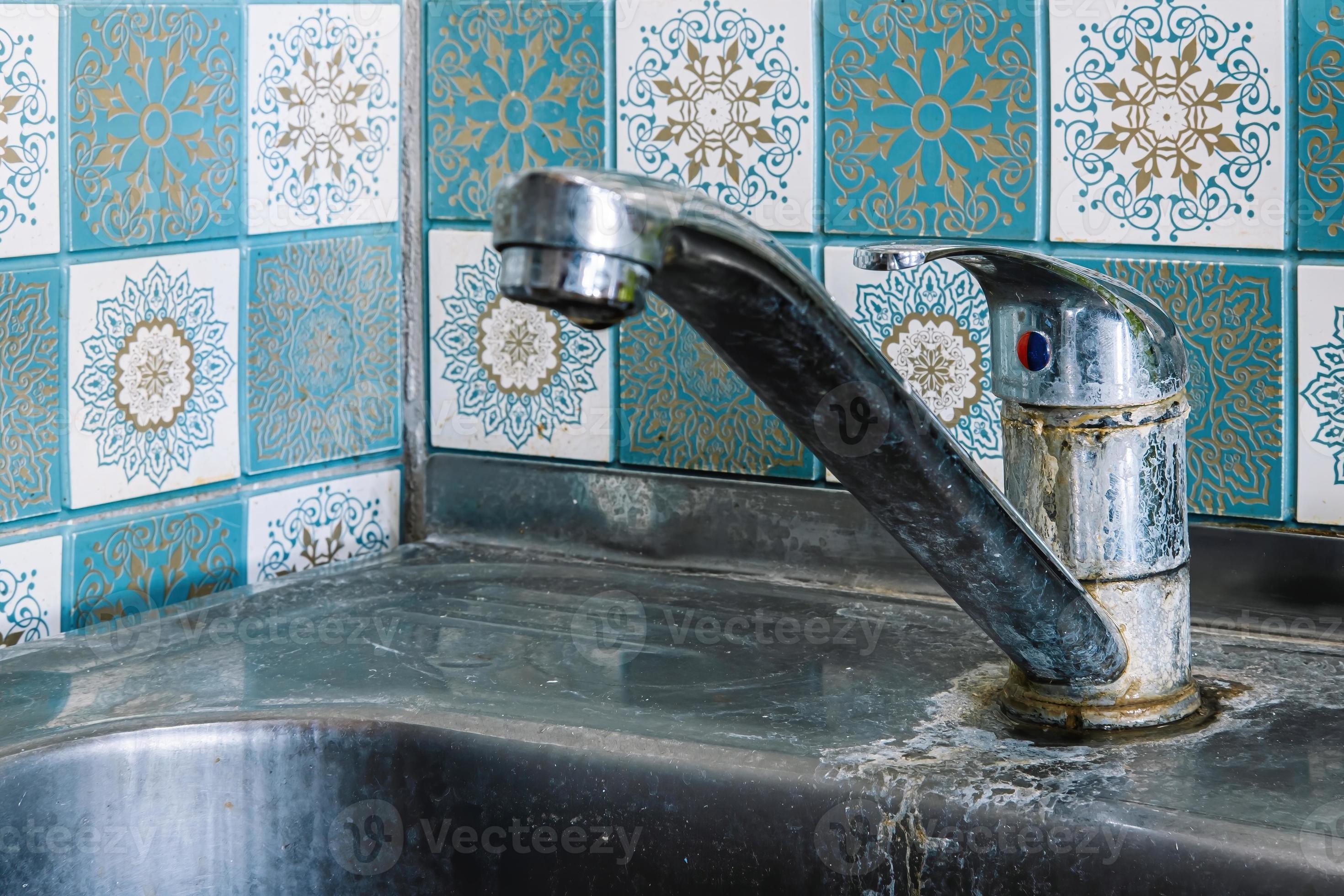Old rusty sink faucet in kitchen. Rust streaks, calcium scale, hard