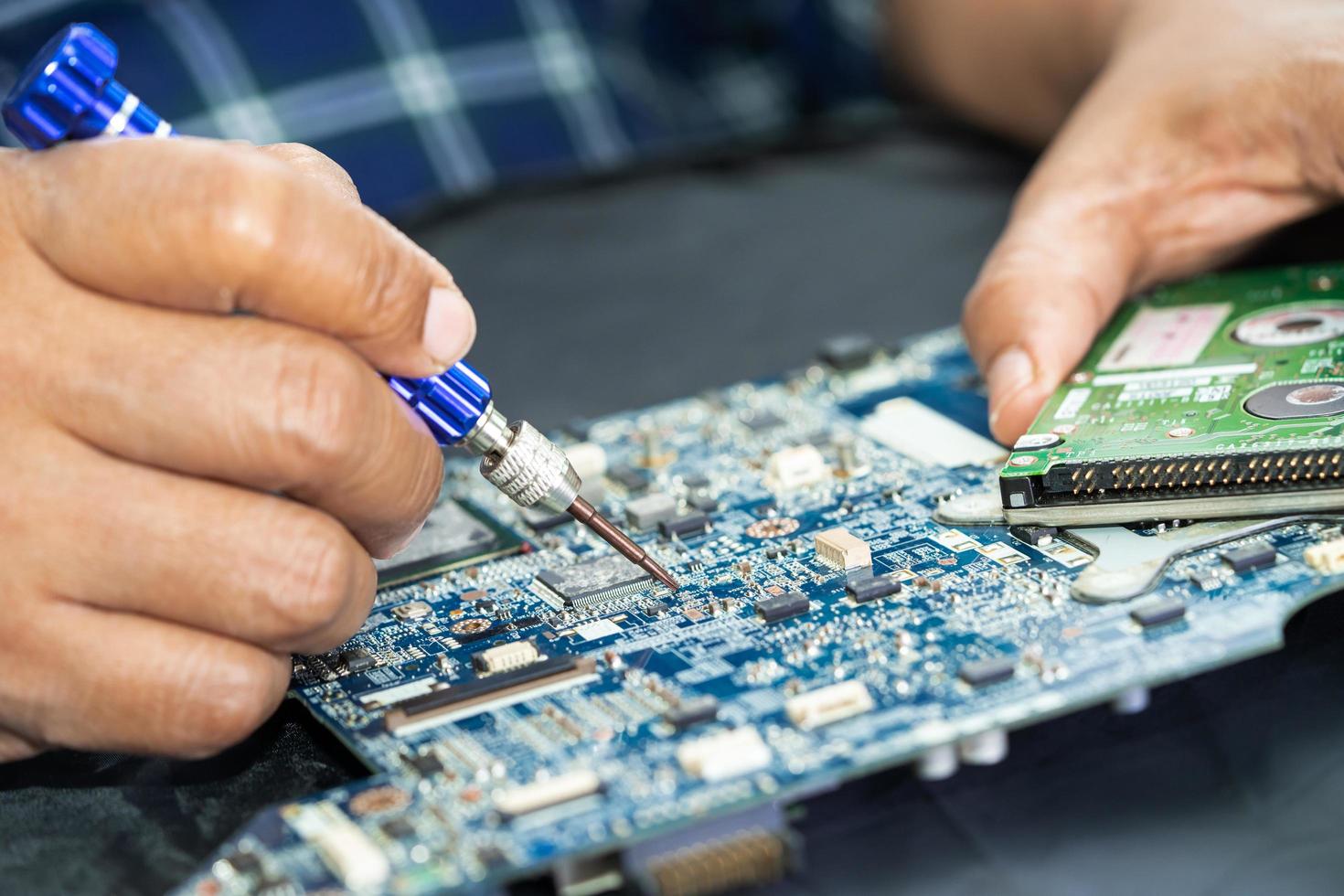Technician repairing inside of printed circuit board PCB by soldering iron. Integrated Circuit. the concept of data, hardware, technician and technology. photo