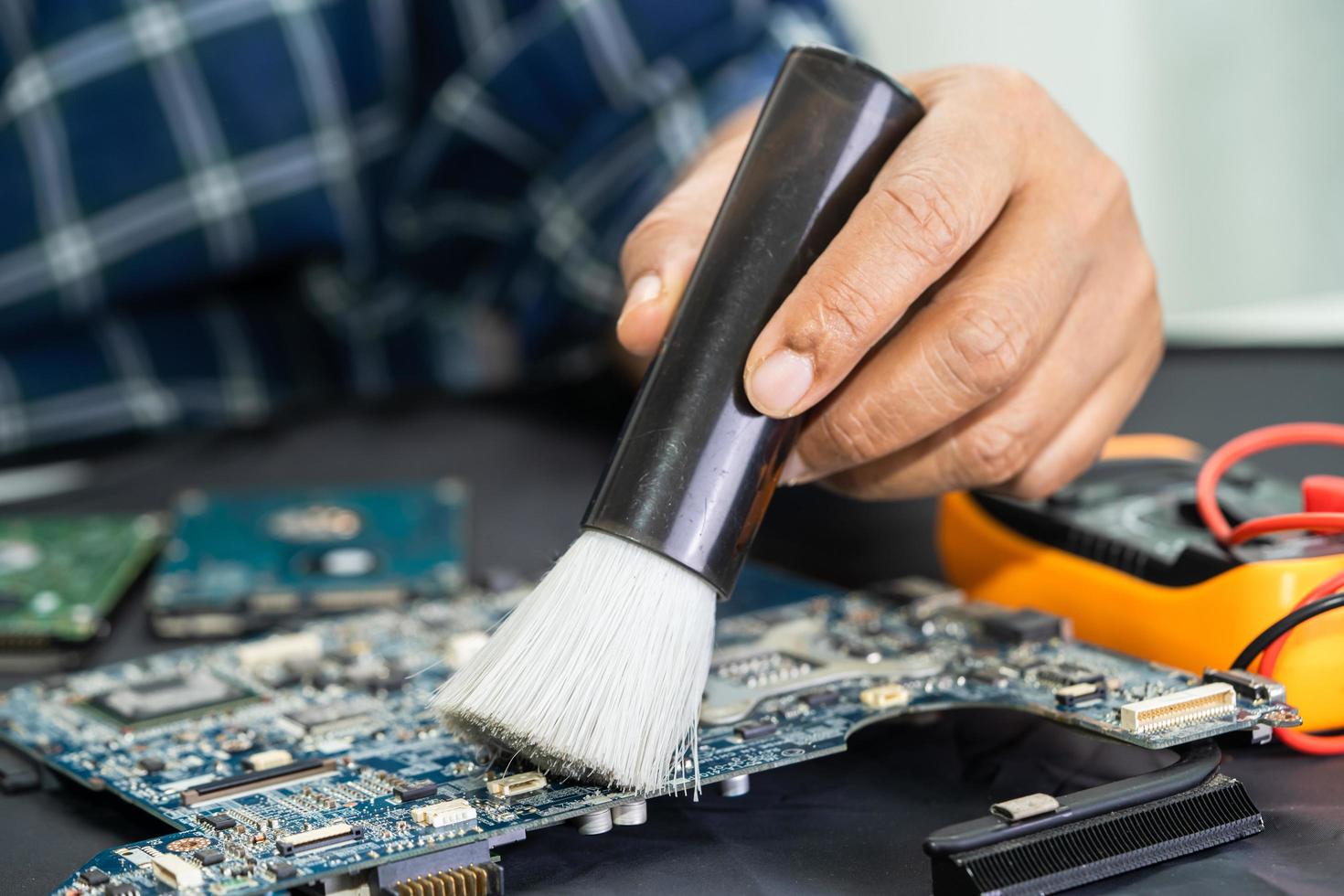 El técnico usa un cepillo y una bola de aire para limpiar el polvo en la placa de circuito de la computadora. reparación de tecnología de actualización y mantenimiento. foto