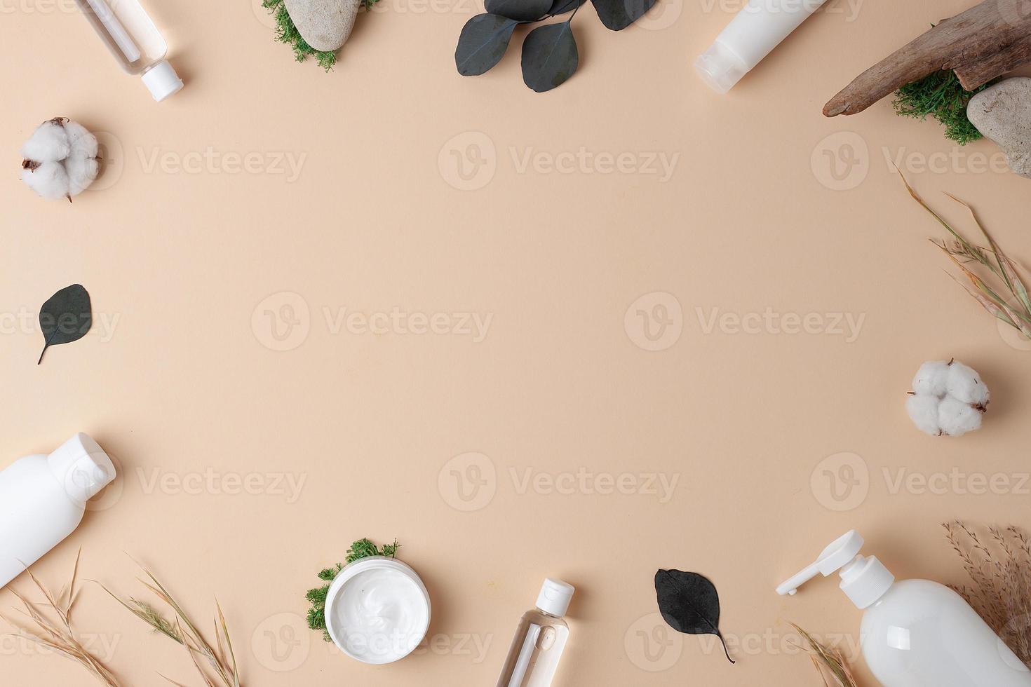 Cosmetic skin care products with flowers and wood on pastel beige background. Flat lay, copy space photo
