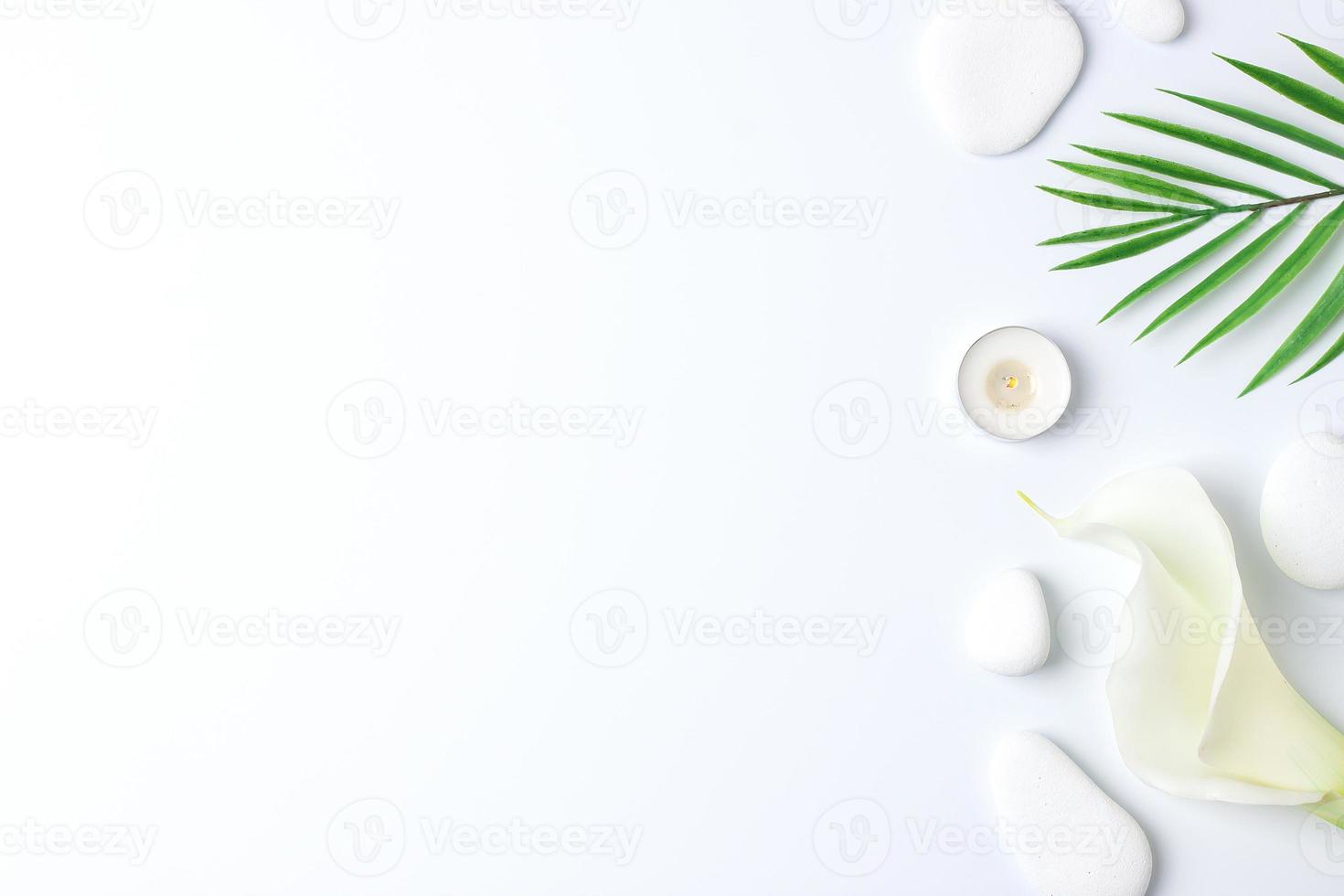 Spa background with white stones, candles, palm leaf and white flower on white. Flat lay,copy space photo