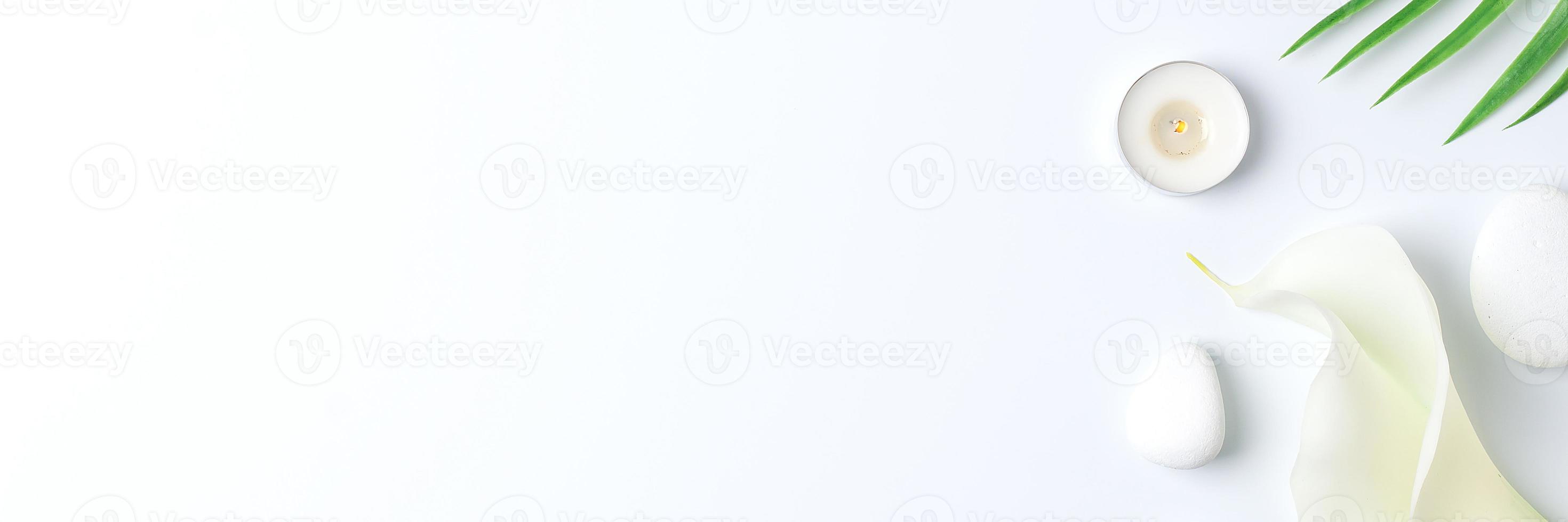 Spa background with white stones, candles, palm leaf and white flower on white. Flat lay,copy space photo
