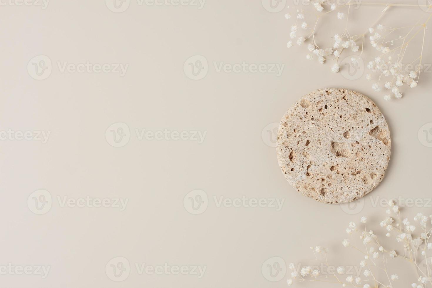 Cosmetic background with flowers and stone podium on pastel beige. Flat lay, copy space photo