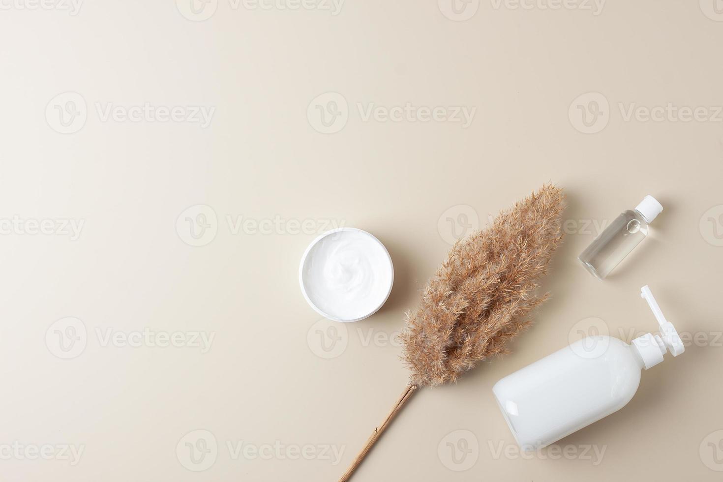Cosmetic skin care products with pampas on pastel beige background. Flat lay, copy space photo