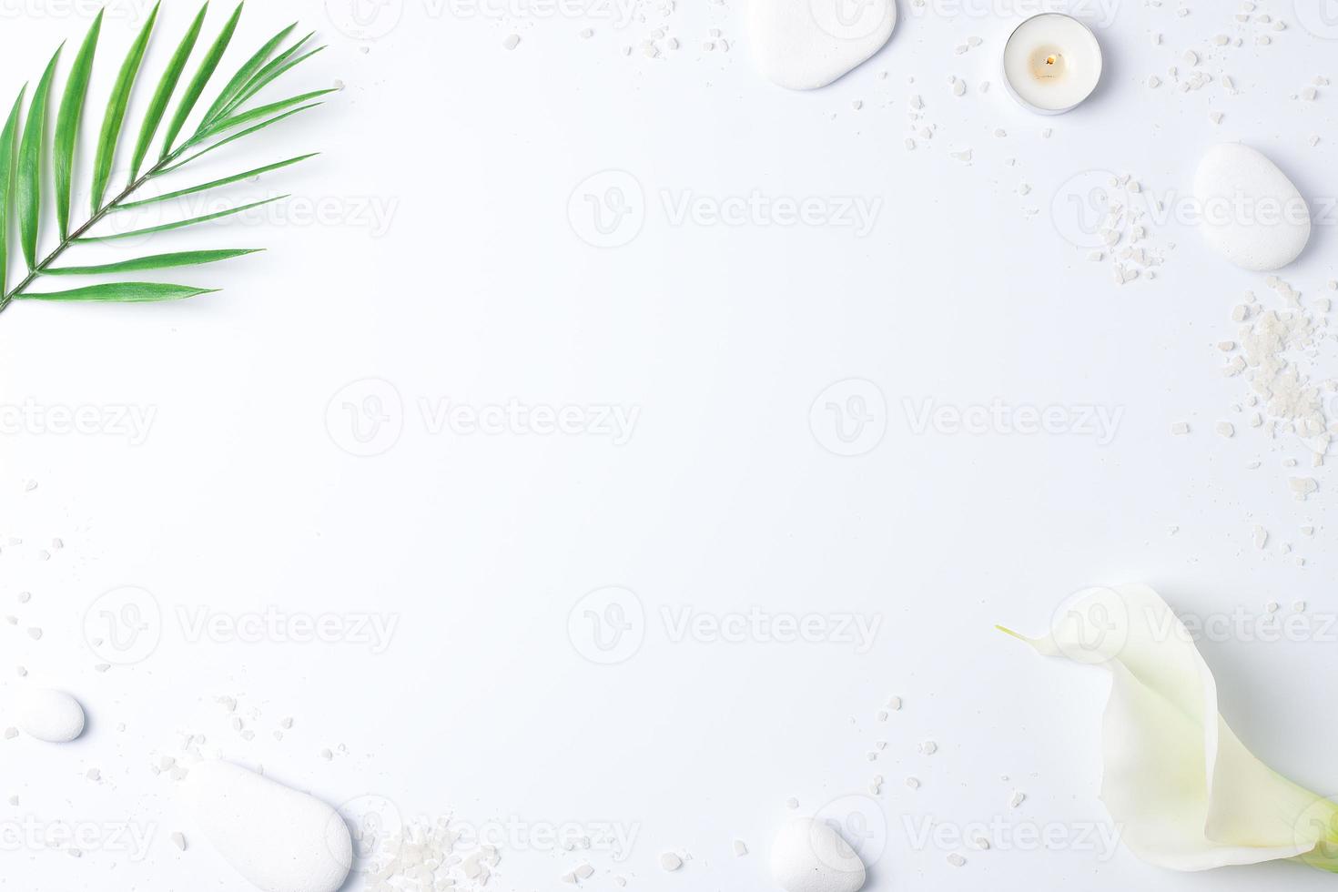 Spa background with white stones, candles, palm leaf and white flower on white. Flat lay,copy space photo