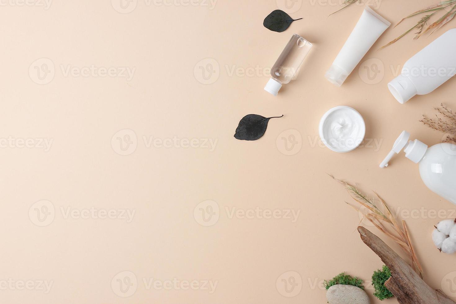 Cosmetic skin care products with flowers and wood on pastel beige background. Flat lay, copy space photo