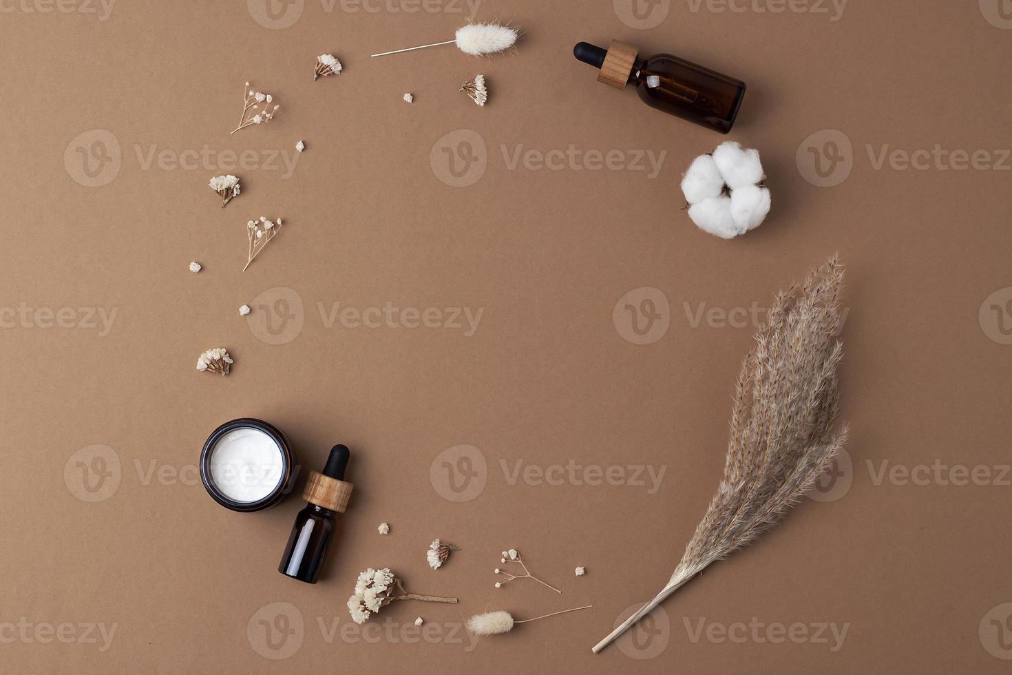 Skin care products on brown background with flowers. Flat lay, copy space. photo